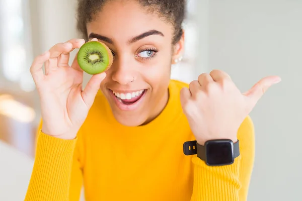 Young African American Girl Eating Green Kiwi Pointing Showing Thumb — ストック写真