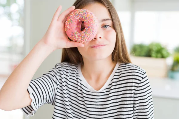 美しいです若いです女の子食べる甘いですピンクドーナツともに自信を持って式上のスマート顔考え深刻な — ストック写真