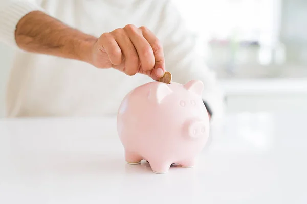 Homem colocando uma moeda dentro de poupança bancária porquinho para investimento — Fotografia de Stock