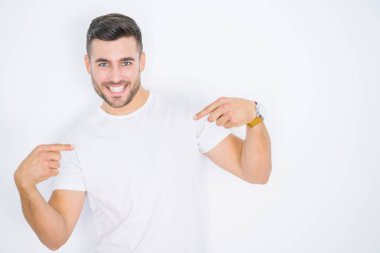 Beyaz izole edilmiş arka plan üzerine günlük beyaz tişört giyen genç yakışıklı bir adam. Kendine güvenen, yüzünde gülümseme olan, kendini gururlu ve mutlu gösteren bir adam..