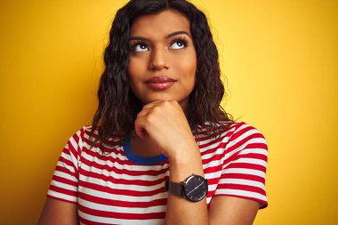 Transseksüel transseksüel kadın izole edilmiş sarı arka plan üzerinde ince tişört giyiyor soru soran ciddi bir yüz, çok karışık bir fikir.