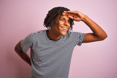 Rasta desenli tişörtlü Afro adam izole edilmiş pembe arka planda dikiliyor çok mutlu ve tebessüm ediyor. Konsept aranıyor.