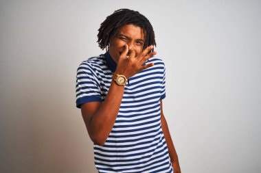 Sarı çizgili mavi polo giyen Afro bir adam izole edilmiş beyaz arka planda dikiliyor pis ve iğrenç bir koku alıyor, nefesi burnunda tutuyor. Kötü koku konsepti.