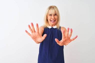 Soyutlanmış beyaz arka plan üzerinde duran zarif mavi elbiseler giyen orta yaşlı bir kadın korku ifadesinden korkuyor ve dehşete düşmüş. El hareketlerini durdur, şok içinde bağır. Panik konsepti.