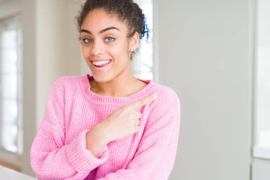 Neşeli bir gülümseme ile el ve parmak kadar yan yüzünde mutlu ve doğal ifade ile işaret yüz afro saçlı güzel genç Afro-Amerikan kadın