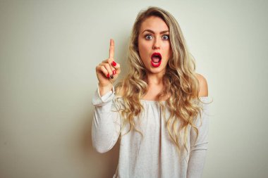 İzole edilmiş beyaz arka planda duran genç ve güzel bir kadın başarılı bir fikri işaret ediyor. Heyecanlı ve mutlu. Bir numara..