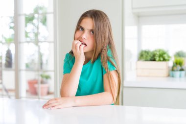 Yeşil tişört giyen genç ve güzel bir kız. Stresli ve gergin görünüyor. Elleri ağızdan tırnak yiyor. Endişe sorunu.