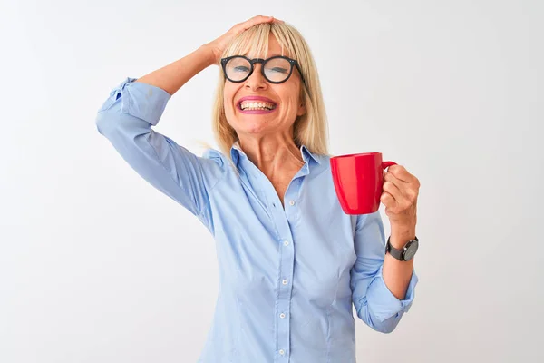 Middle age businesswoman wearing glasses drinking coffee over isolated white background stressed with hand on head, shocked with shame and surprise face, angry and frustrated. Fear and upset for mistake.