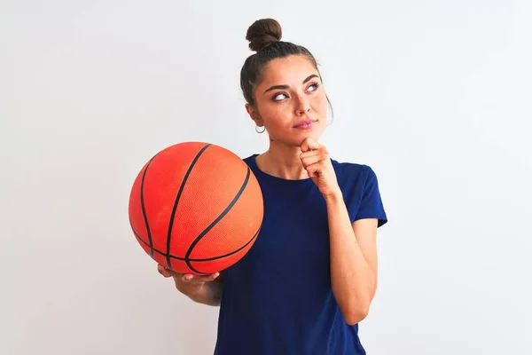 年轻漂亮的女运动员抱着篮球在孤独的白色背景下严肃地思考着问题 非常混乱的想法 — 图库照片