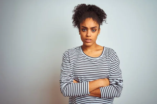 African american woman wearing navy striped t-shirt standing over isolated white background skeptic and nervous, disapproving expression on face with crossed arms. Negative person.