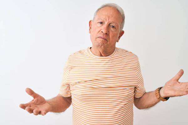 Senior grey-haired man wearing striped t-shirt standing over isolated white background clueless and confused with open arms, no idea concept.