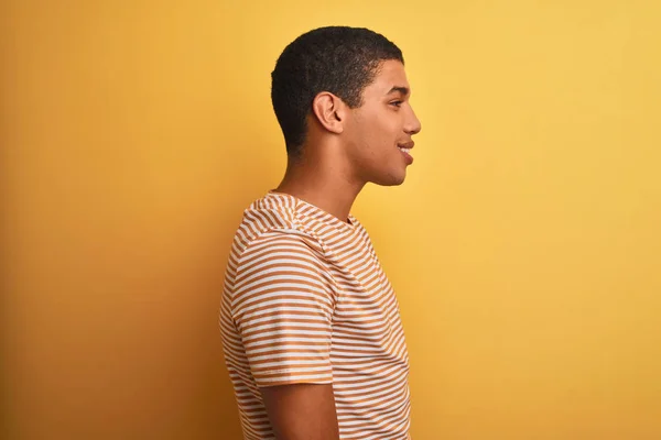 年轻英俊的阿拉伯男子穿着条纹T恤 站在孤立的黄色背景上 面带微笑 放松自己的形象 — 图库照片