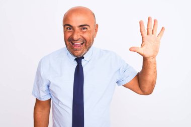 Orta yaşlı iş adamı, izole edilmiş beyaz arka plan üzerinde duran kravat takıyor ve beş numaralı parmaklarıyla işaret ederken kendinden emin ve mutlu gülümsüyor..
