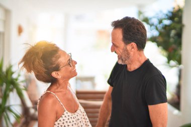 Orta yaşlı, güzel bir çift terasta durup konuşuyor ve gülümsüyor.