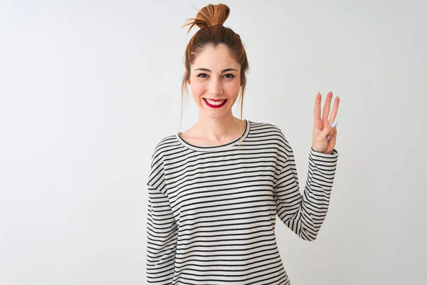 身穿海军条纹T恤的红头发女人站在孤立的白色背景上 露出并用第三指尖指尖 同时带着自信和快乐的笑容 — 图库照片