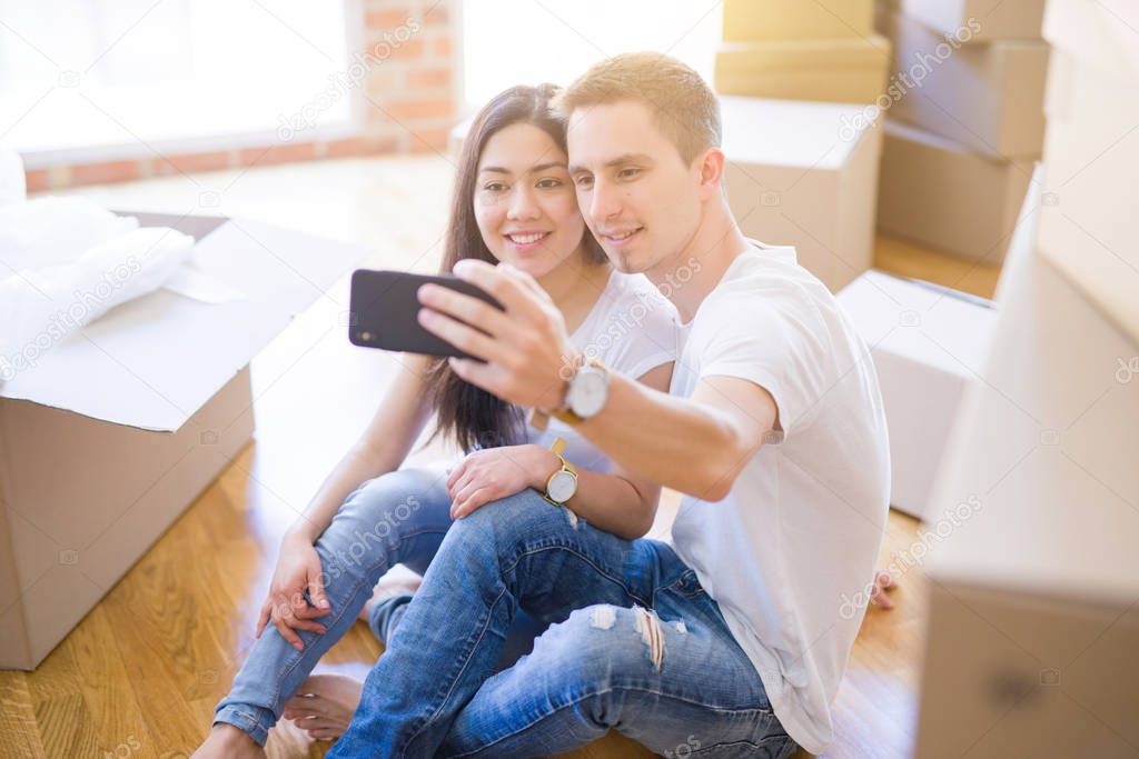 Young beautiful couple standing at new home around cardboard boxes