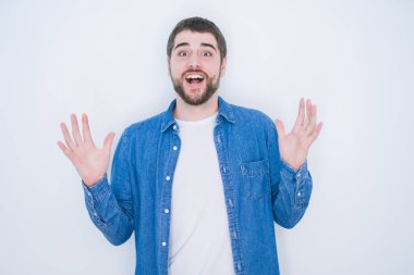 Beyaz izole edilmiş arka planda kot ceket giyen genç, yakışıklı İspanyol adam çılgın ve başarıyı kollarını kaldırıp heyecanla haykırarak kutluyor. Kazanan konsept