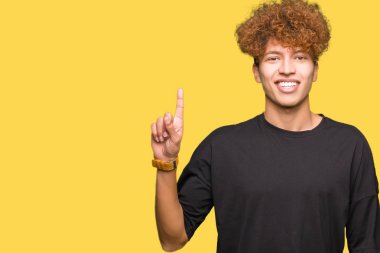 Genç yakışıklı adam ile afro saç giyen siyah t-shirt gösteren ve işaret yukarıya ile parmak sayı bir süre gülümseyen emin ve mutlu.