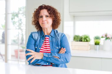 Kıvırcık saçlı, evde kot ceket giyen, kuşkucu ve gergin orta yaşlı bir kadın. Yüzünde çapraz kollarıyla onaylamayan bir ifade var. Negatif kişi.