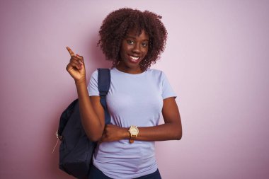 Sırt çantasıyla gezen Afrikalı genç bir Afrikalı turist. Yüzünde kocaman bir gülümseme, elleri ve parmaklarıyla kameraya bakıyor..