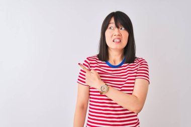 İzole edilmiş beyaz arka plan üzerinde kırmızı çizgili tişört giyen genç, güzel Çinli kadın endişeli ve endişeli bir ifade sergiliyor.