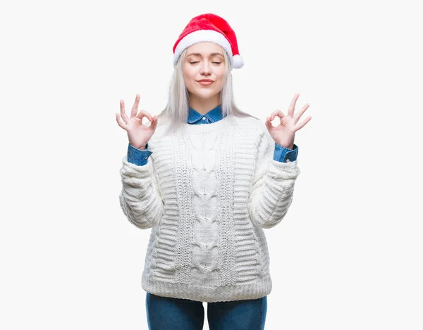 孤立した背景の上身に着けているクリスマスの帽子を若いブロンドの女性リラックスして瞑想の指ジェスチャーをやって閉じた目と笑顔します ヨガの概念 — ストック写真