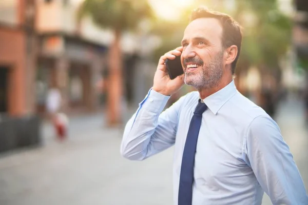 Middle age handsome businessman talking on the smartphone smiling