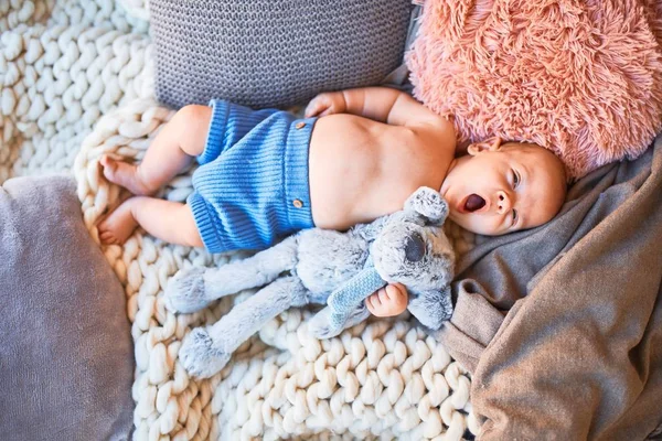 可爱的婴儿躺在沙发上 盖在家里的毛毯上 新生儿的放松和休息舒适与洋娃娃 — 图库照片