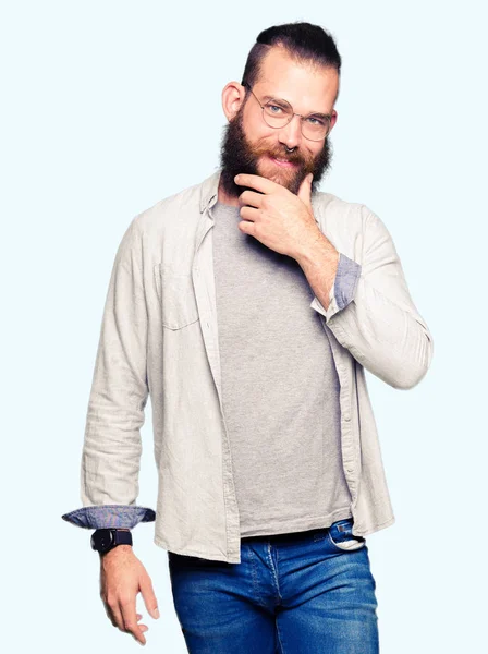 Genç sarışın adam gözlüklü emin çapraz kollar ve çeneme kaldırdı el ile gülümseme ile kameraya bakıyor. Pozitif düşünce.