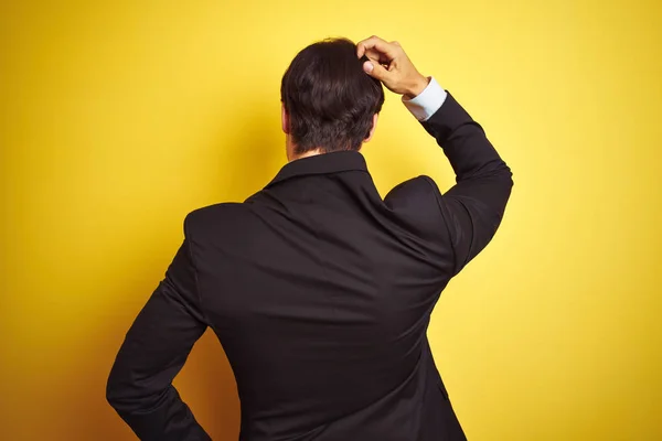年轻英俊的商人 身穿西服 打着领带 站在孤立的黄色背景上 背对着自己 头脑清醒地思考问题 — 图库照片
