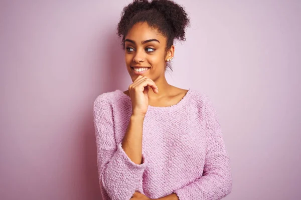 Young african american woman wearing winter sweater standing over isolated pink background with hand on chin thinking about question, pensive expression. Smiling and thoughtful face. Doubt concept.