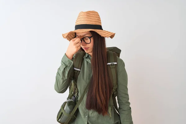 Chinese hiker woman wearing canteen hat glasses backpack over isolated white background tired rubbing nose and eyes feeling fatigue and headache. Stress and frustration concept.