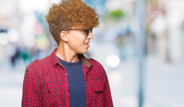 Yakışıklı genç afro saçlı uzak tarafına yüzünde, doğal ifade gülümseme ile seyir güneş gözlüğü takıyor. Kendine güvenen gülüyor.