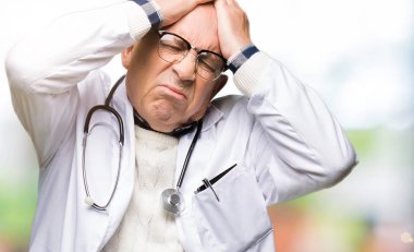 Ağrı ve migren çünkü baş ağrısı umutsuz ve vurguladı tıbbi ceket giyen yakışıklı kıdemli Doktor adam. Eller baş.