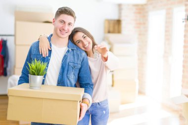 Güzel genç çift aşık ve yeni ev, yeni bir daireye hareket mutlu gülümseyen anahtarları gösteren sarılma