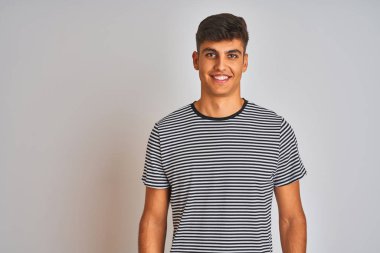 Genç Hintli bir adam, donanma çizgili tişört giyiyordu. Yüzünde mutlu ve havalı bir gülümsemeyle izole edilmiş beyaz bir arka planın üzerinde duruyordu. Şanslı kişi..