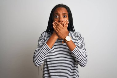 İzole edilmiş beyaz arka planda duran çizgili tişört giyen genç Afrikalı Amerikalı kadın yanlışlıkla ağızlarını kapatarak şok geçirdi. Gizli konsept.