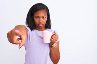 Genç Afrikalı Amerikalı kadın izole edilmiş arka planda bir fincan kahve içerek kamerayı işaret ediyor ve sen, el işareti, ön taraftan pozitif ve kendinden emin bir hareket.