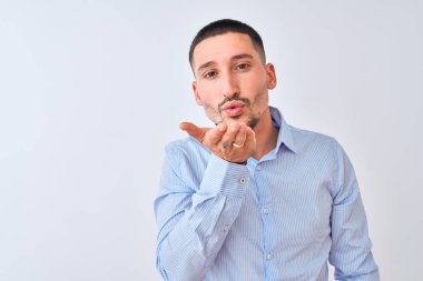Genç yakışıklı iş adamı, izole edilmiş arka planda durup kameraya bakarak havada bir öpücük savuruyor ve sevimli ve seksi oluyor. Aşk ifadesi.