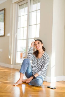 Genç güzel kadın düşünme ve evde yerde oturan çene üzerinde bir el ile merak