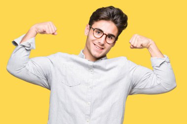 Kol kasları gururlu gülümseyen gösterilen izole arka plan üzerinde gözlük takan yakışıklı delikanlı. Fitness kavramı.