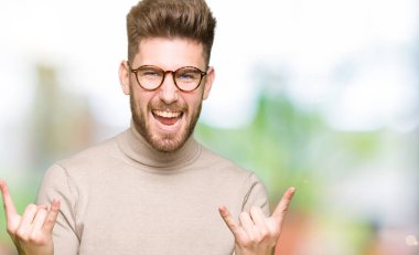 Genç yakışıklı iş adamı deli ifade rock simge elle yapıyor ile bağırarak gözlük takıyorum. Müzik yıldızı. Ağır kavramı.