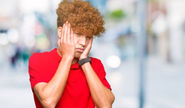 Kırmızı t-shirt yorgun el yüz, depresyon ve üzüntü, kapsayan giyen afro saçlı Genç yakışıklı adam üzgün ve sorun için tahriş