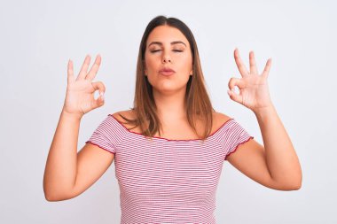 Güzel bir genç kadının portresi izole edilmiş beyaz arka planda duruyor rahatla ve gözleri kapalı parmaklarıyla meditasyon hareketi yaparken gülümse. Yoga konsepti.