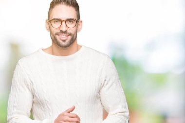 Arka plan eller üzerinde gözlük takan genç yakışıklı adam birlikte izole ve rahat ve neşeli gülümseyen parmak çarpı işareti. Başarı ve iyimser