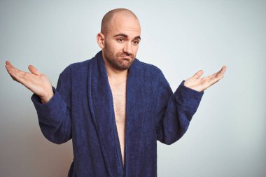 Mavi bornoz giyen genç bir adam, sakin bir yaşam tarzı izole edilmiş bir geçmişi var. Kolları ve elleri havada, kafası karışmış bir yüz ifadesi var. Şüphe kavramı.