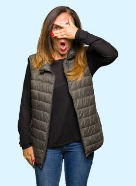 Kış yelek giyen güzel orta yaş kadın el ile yüz ve gözler kapsayan şok göz, utanmış ifade ile parmaklar bakarak.