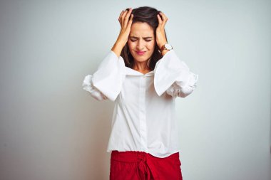 Beyaz izole arka plan üzerinde ayakta t-shirt giyen genç güzel kadın çaresiz baş ağrısı muzdarip ve ağrı ve migren nedeniyle vurguladı. Eller baş.