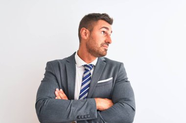 Takım elbiseli ve kravatlı genç yakışıklı bir iş adamı kollarını kavuşturup kollarını kavuşturup kendinden emin bir şekilde yan tarafa bakıyor.