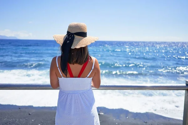 Young beautiful woman looking at the sea enjoying summer vacation at the beach